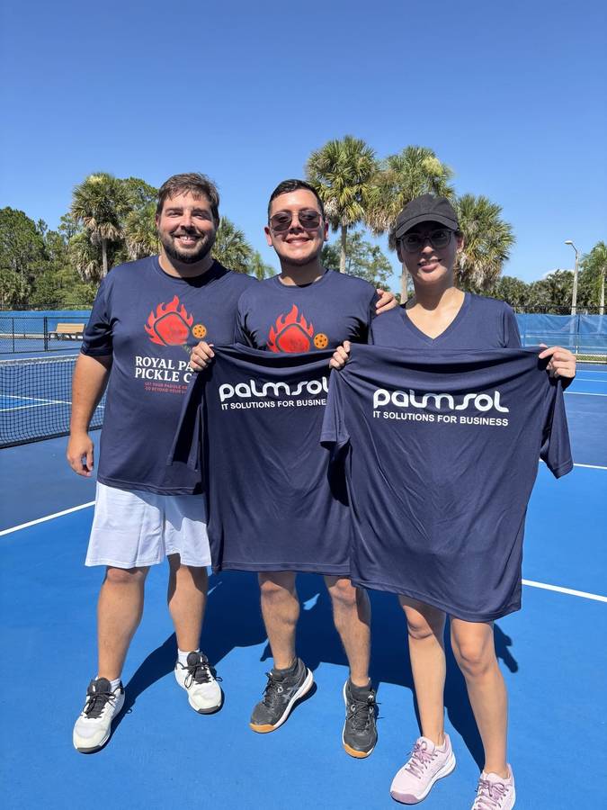 PalmSol team holding branded shirts on the pickleball court